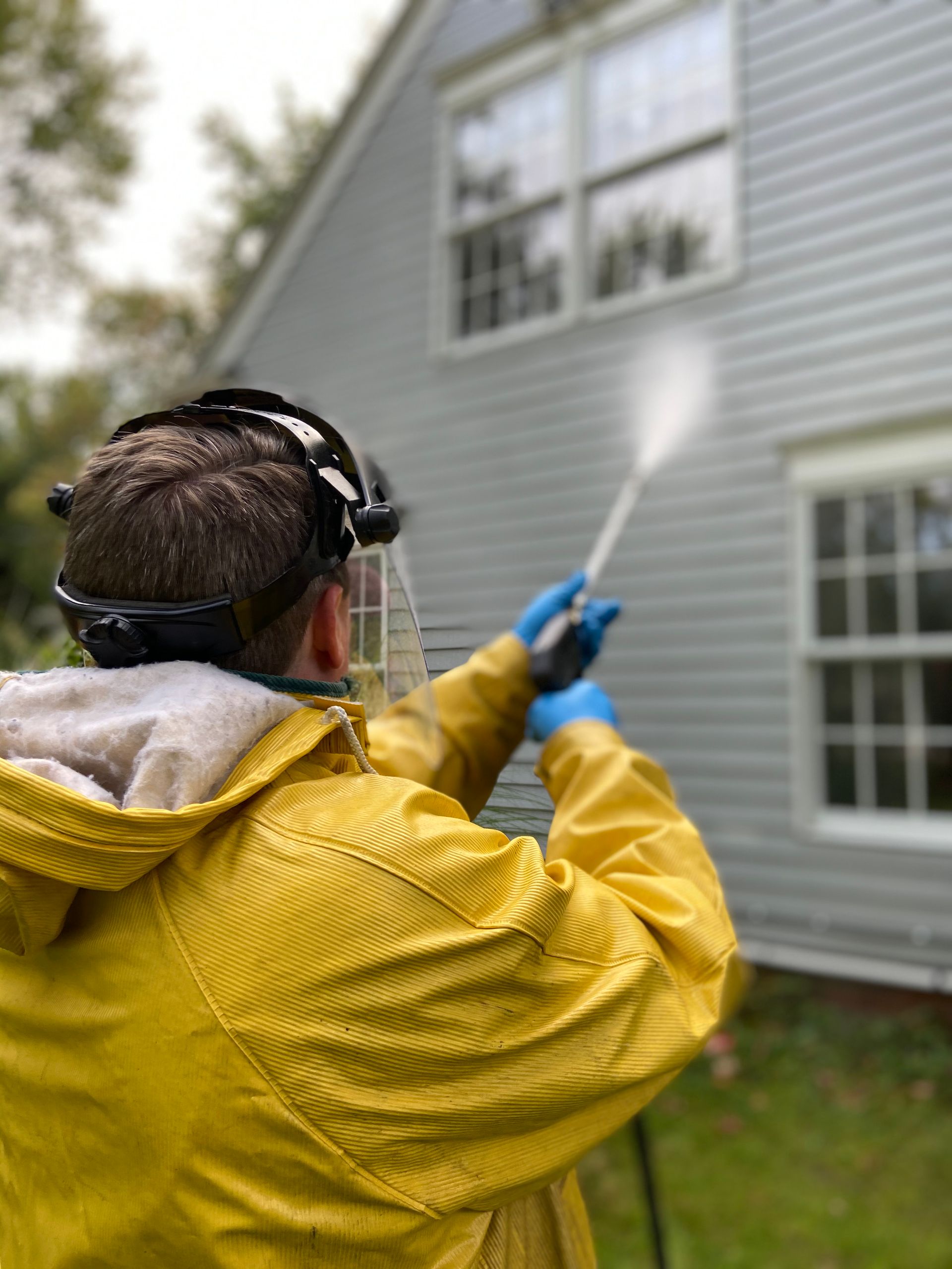 Illustrative photo: technician pressure washing house siding